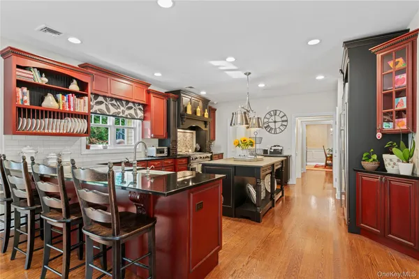 a kitchen with stainless steel appliances granite countertop a stove a refrigerator a kitchen island with chairs and wooden floor