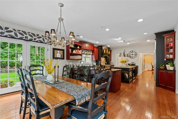 a view of a dining room and livingroom with furniture wooden floor a rug a painting and a chandelier