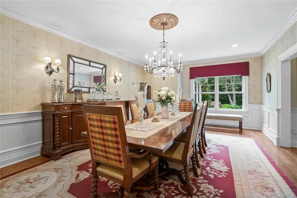a dining room with wooden floor a chandelier a wooden table and chairs