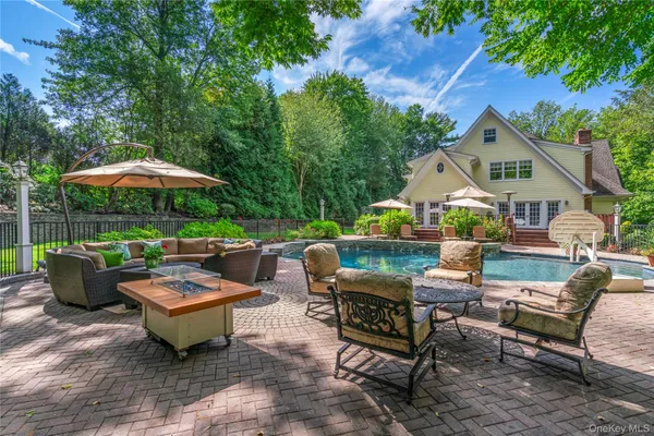 a view of a patio with couches table and chairs under an umbrella with a barbeque
