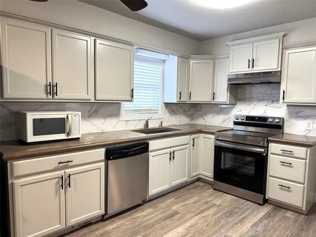 a kitchen with cabinets appliances and a window