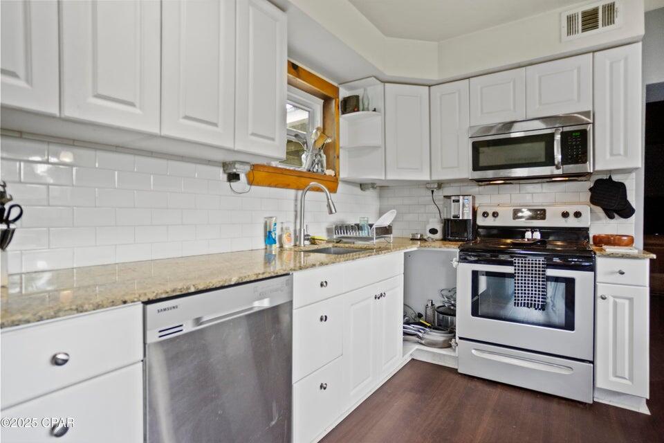 133 Devane Road Chattahoochee, FL 32324 - Photo 24 of 39 a kitchen with stainless steel appliances granite countertop a sink a stove and microwave with wooden floor