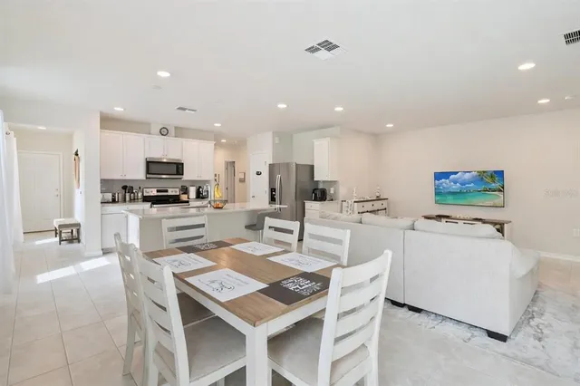 a kitchen with stainless steel appliances kitchen island granite countertop a sink a stove a dining table and chairs