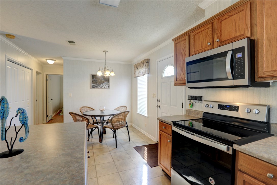 9755 61st Terrace Sebastian, FL 32958 - Photo 16 of 35 a kitchen with stainless steel appliances a stove a microwave a dining table and chairs