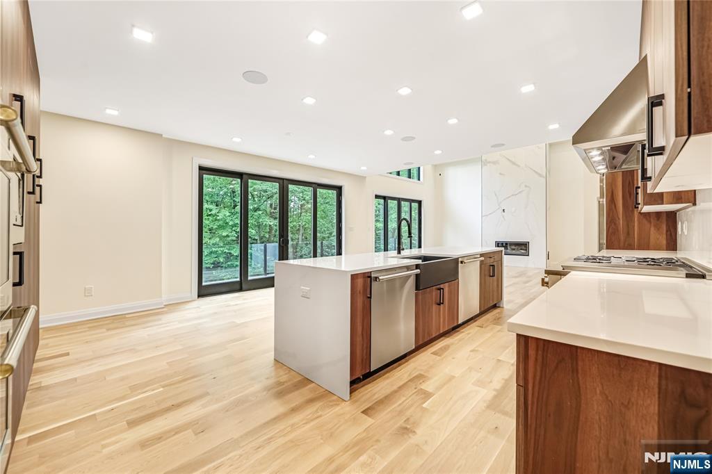 10 Big Ramapo Road Saddle River, NJ 07458 - Photo 11 of 44 a large white kitchen with stainless steel appliances kitchen island a large counter top and a wooden floors