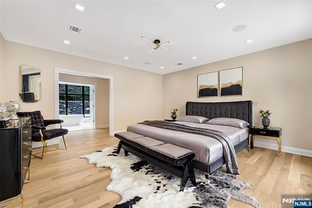 10 Big Ramapo Road Saddle River, NJ 07458 - Photo 34 of 44 a spacious bedroom with a bed a table and wooden floor