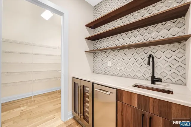 a large white kitchen with stainless steel appliances kitchen island a large counter top and a wooden floors