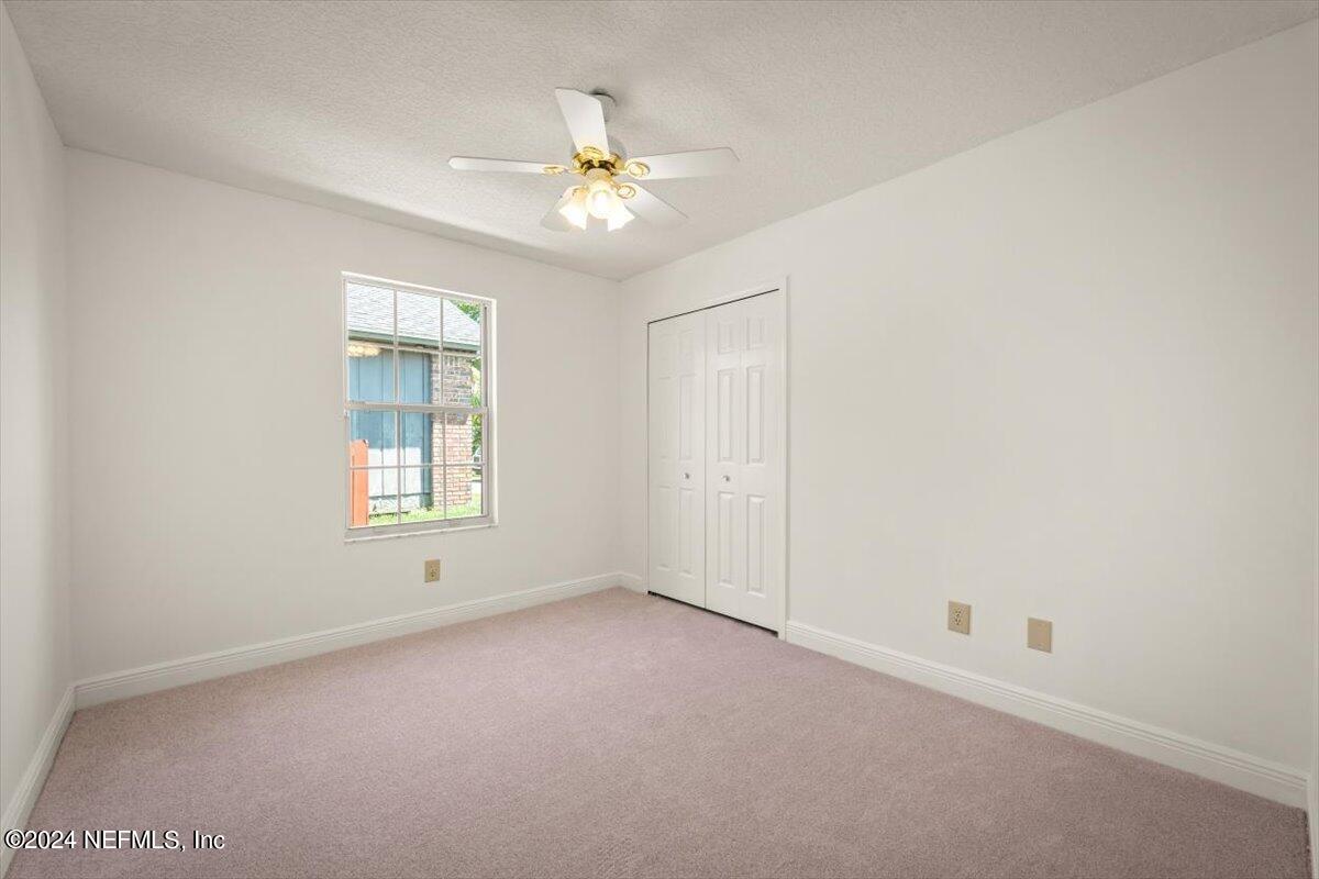 10967 Heathfield Road Jacksonville, FL 32225 - Photo 22 of 39 an empty room with a chandelier fan and windows