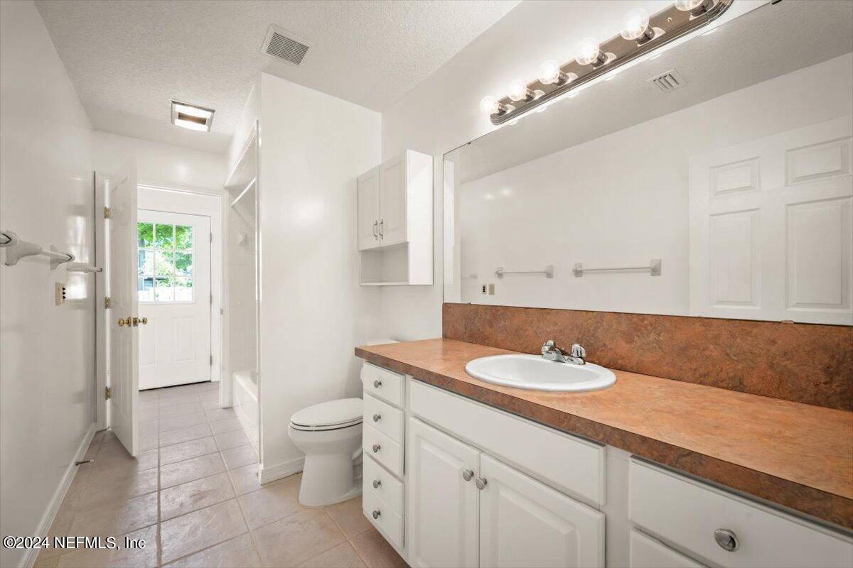 10967 Heathfield Road Jacksonville, FL 32225 - Photo 27 of 39 a bathroom with a granite countertop sink a toilet and a shower