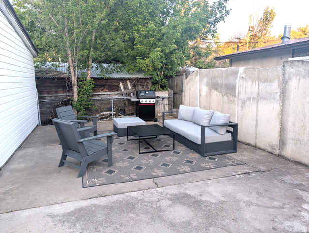 136 East 300 South Logan, UT 84321 - Photo 19 of 26 Concrete patio area featuring a white siding exterior, mature trees, and a concrete perimeter wall