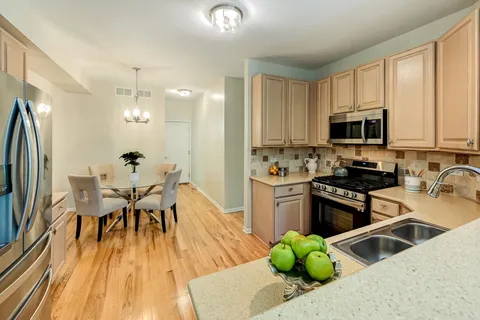a kitchen with stainless steel appliances granite countertop a stove top oven a sink dishwasher a dining table and chairs with wooden floor