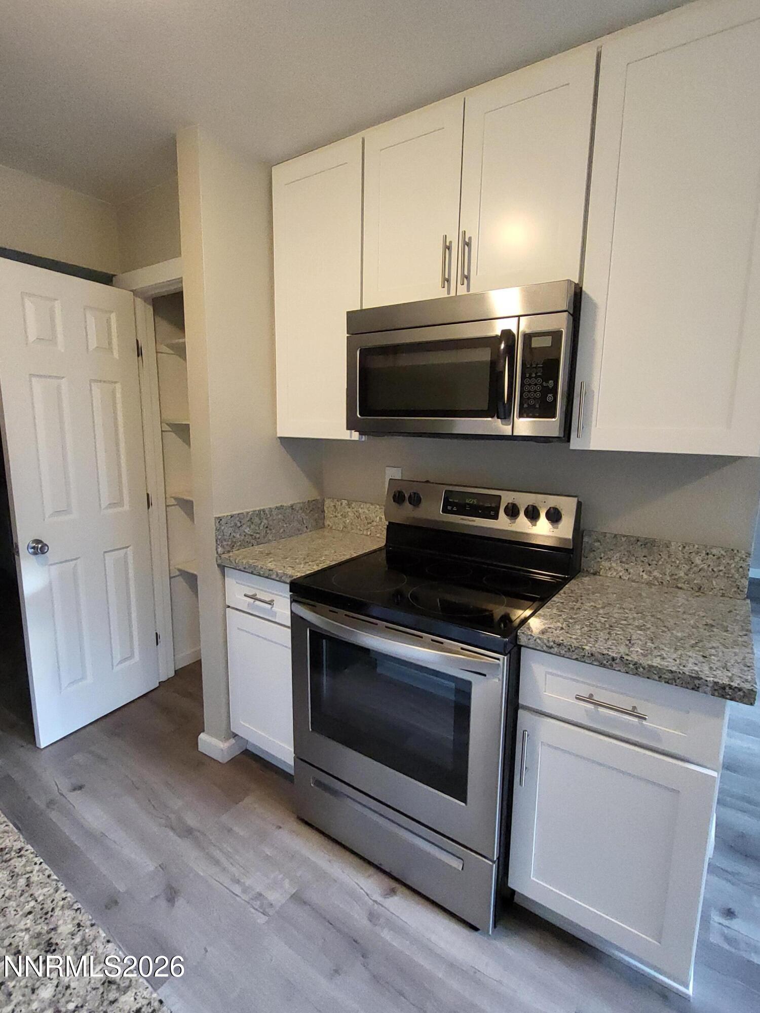4606 Neil Road, Unit 197 Reno, NV 89502 - Photo 22 of 26 a kitchen with granite countertop cabinets stainless steel appliances and wooden floor