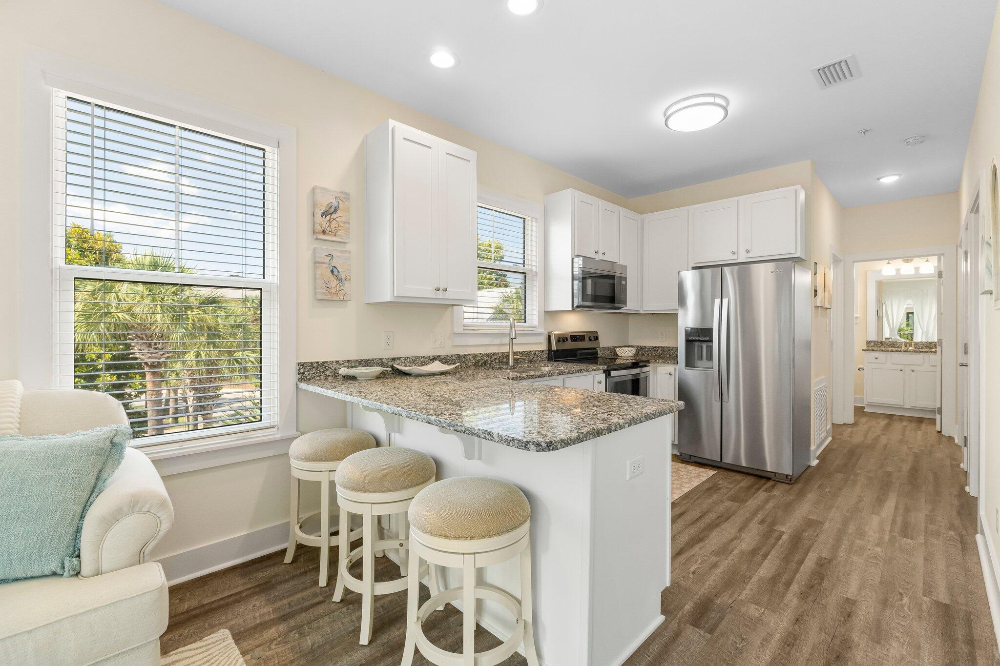 3958 West County Highway 30A, Unit 124 Santa Rosa Beach, FL 32459 - Photo 11 of 51 a kitchen with kitchen island granite countertop wooden floors and white stainless steel appliances