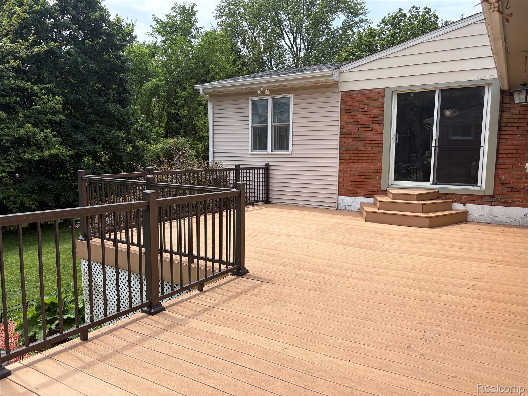 1451 Wilshire Road Haslett, MI 48840 - Photo 12 of 42 Spacious outdoor deck featuring composite decking, dark railings, and a three-step entry to sliding glass doors