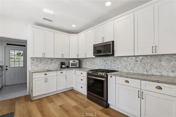 a kitchen with granite countertop white cabinets and stainless steel appliances