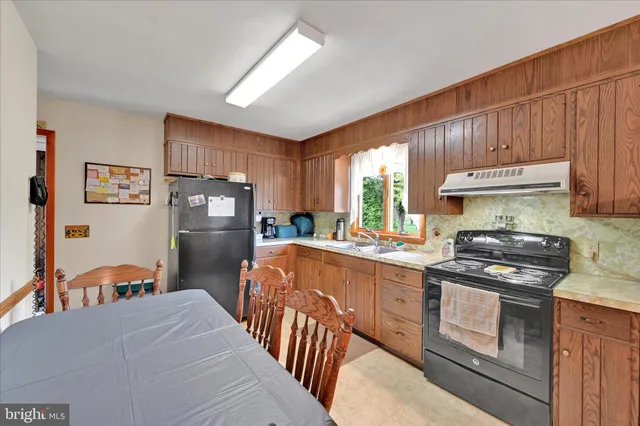 a kitchen with stainless steel appliances granite countertop a refrigerator a stove a sink dishwasher and wooden cabinets with wooden floor