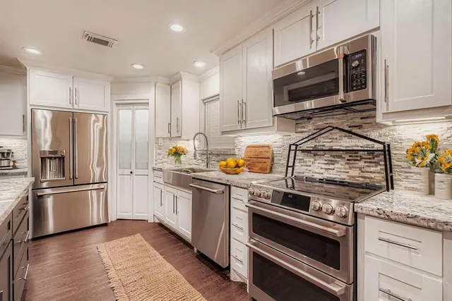 a kitchen with stainless steel appliances granite countertop a stove a refrigerator and a microwave