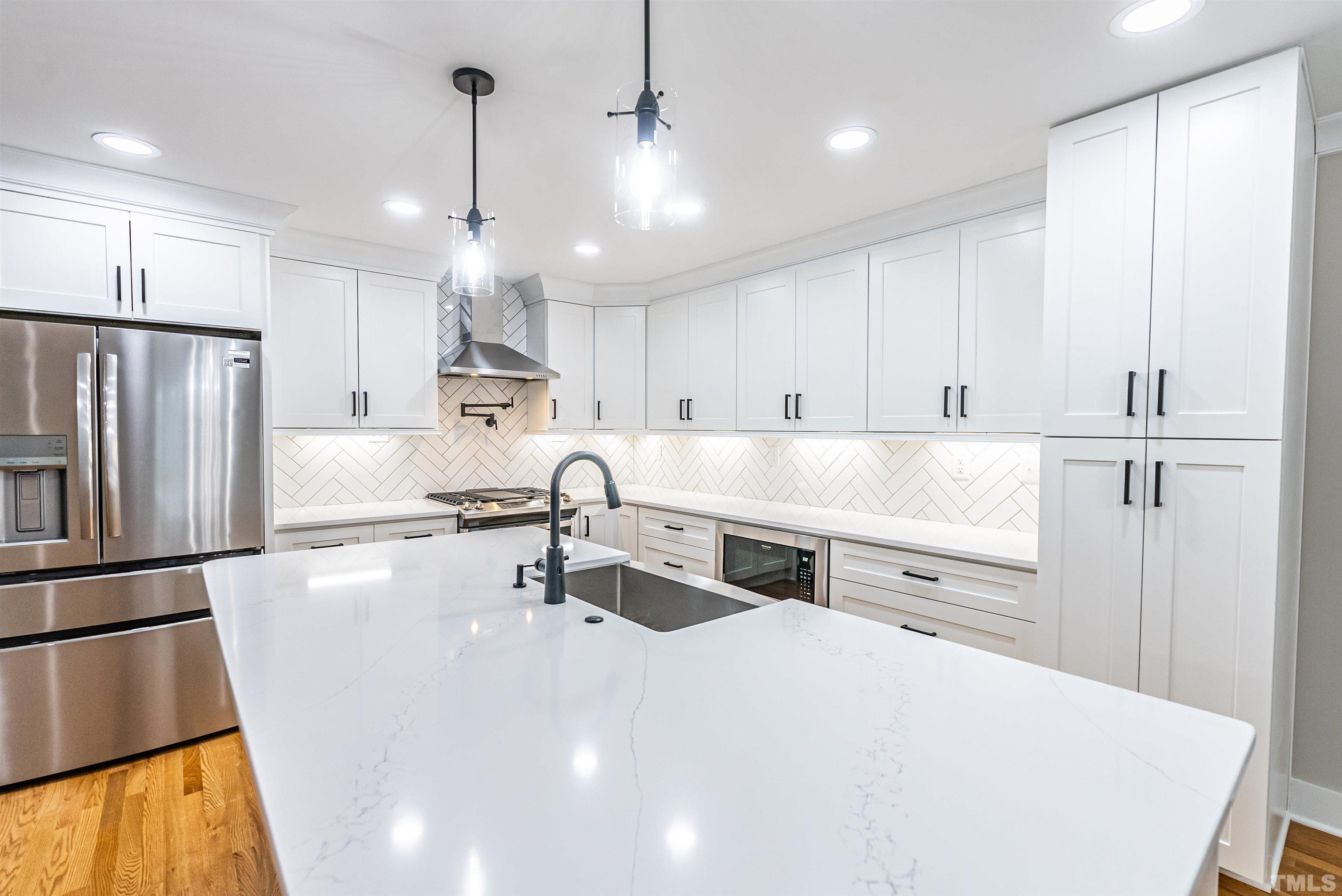 5405 Emerson Drive Raleigh, NC 27609 - Photo 12 of 46 a kitchen with stainless steel appliances a stove a sink a refrigerator and white cabinets with wooden floor