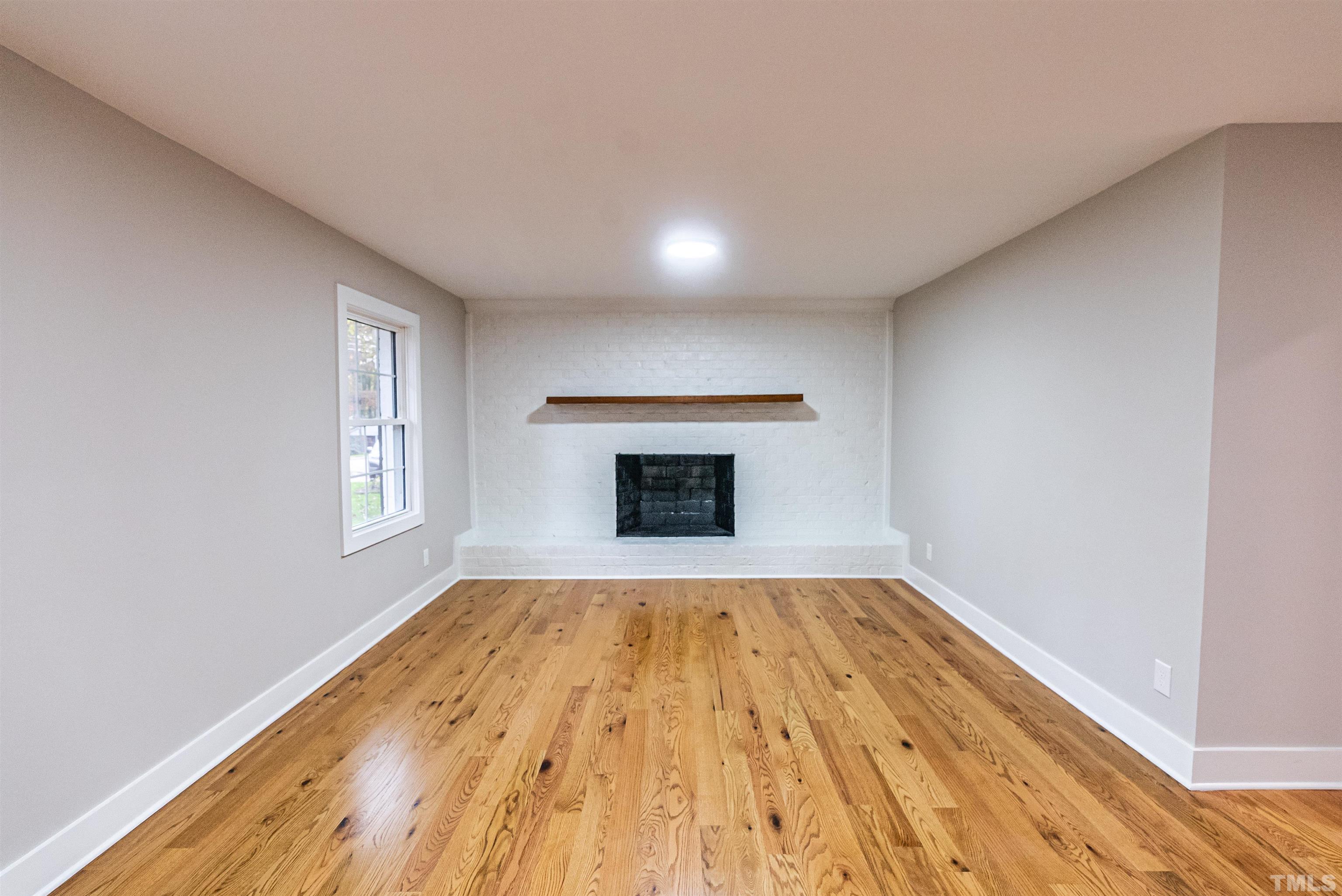 5405 Emerson Drive Raleigh, NC 27609 - Photo 27 of 46 a view of empty room with wooden floor and fireplace