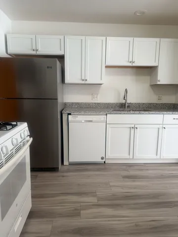 a kitchen with granite countertop white cabinets and white appliances