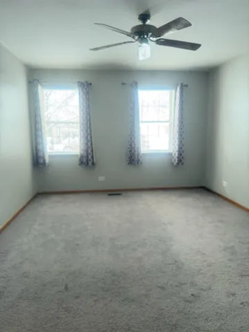an empty room with a window and a ceiling fan