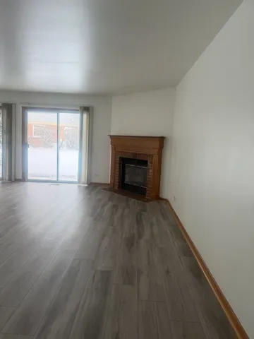 an empty room with wooden floor fireplace and windows