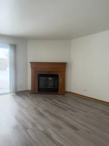 a view of empty room with wooden floor and fireplace