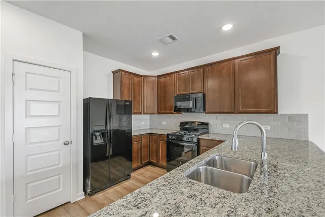 a kitchen with granite countertop stainless steel appliances a refrigerator stove and sink