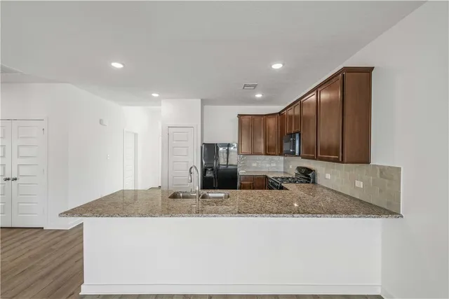 a kitchen with kitchen island granite countertop wooden cabinets a refrigerator and a sink