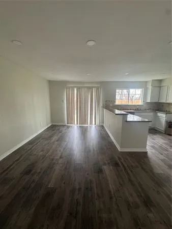 a view of kitchen and empty room with wooden floor