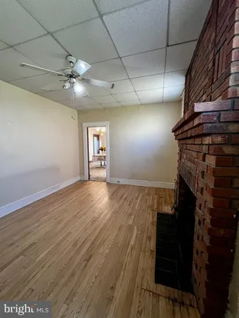 a view of an empty room with a fireplace and a chandelier fan