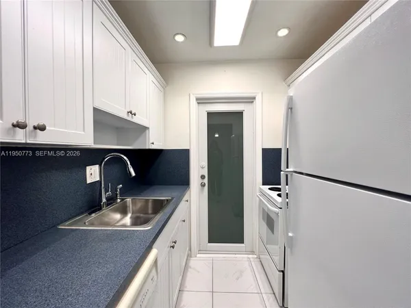 a kitchen with a sink a refrigerator and cabinets