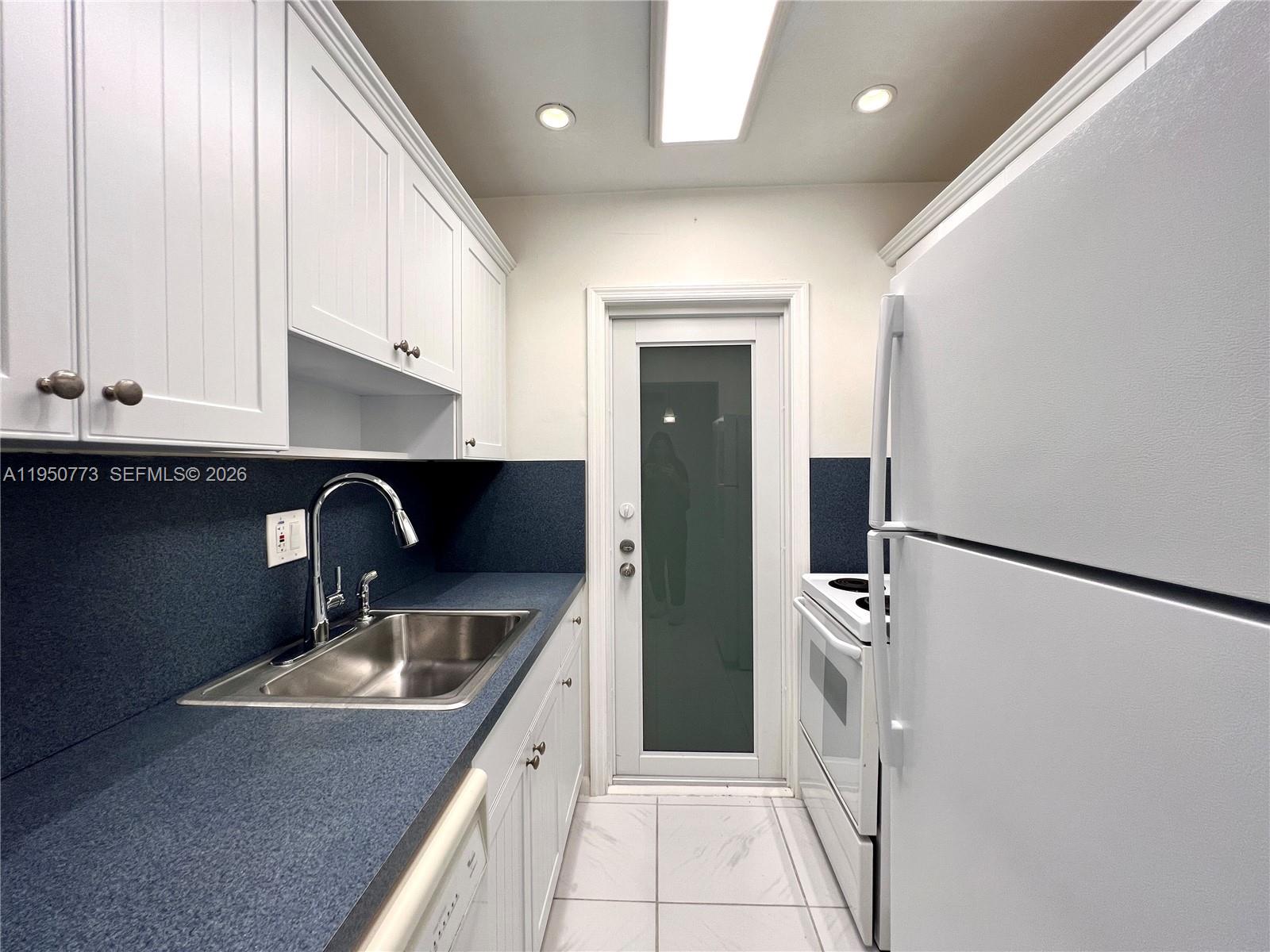 255 Sunrise Drive, Unit 308 Key Biscayne, FL 33149 - Photo 7 of 18 a kitchen with a sink a refrigerator and cabinets