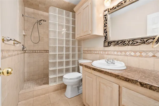 a bathroom with a granite countertop sink a toilet and shower