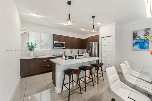 a kitchen with stainless steel appliances granite countertop a sink a stove a refrigerator cabinets and chairs