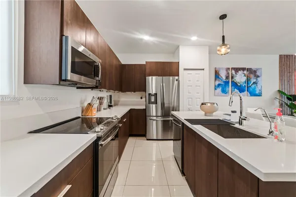 a kitchen with stainless steel appliances a sink dishwasher a refrigerator a microwave oven with cabinets and wooden floor