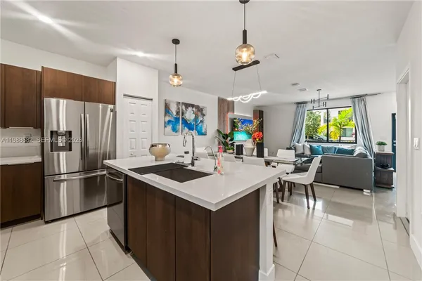 a kitchen with stainless steel appliances granite countertop a sink dishwasher a refrigerator and a dining table with chairs