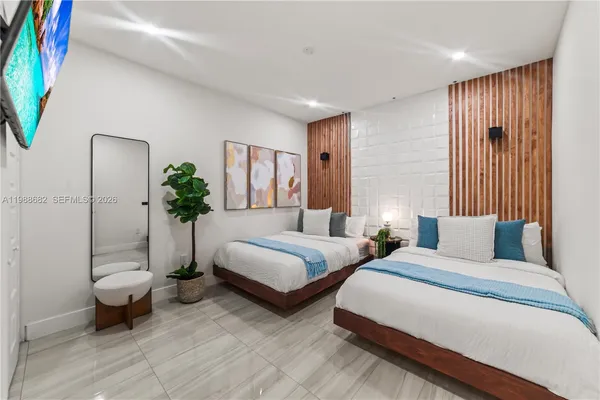 a spacious bedroom with two beds and a potted plant