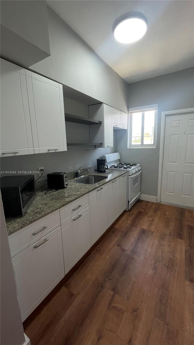 8100 Harding Avenue, Unit 508 Miami Beach, FL 33141 - Photo 16 of 20 a kitchen with granite countertop white cabinets and white appliances