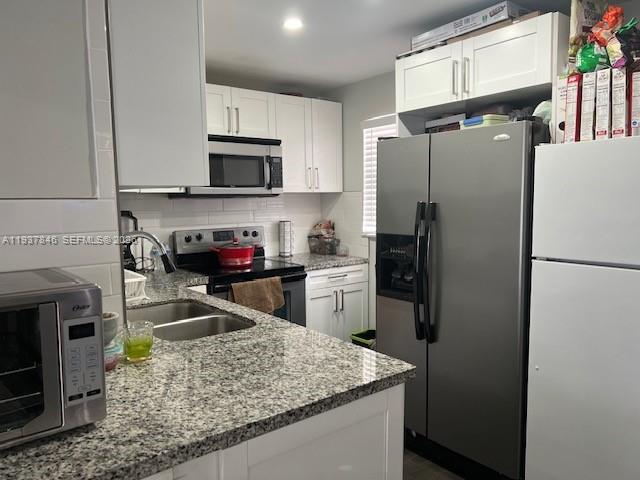a kitchen with stainless steel appliances granite countertop a refrigerator stove microwave and sink