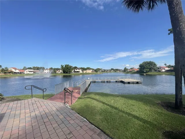 a view of pool with lawn chairs and large trees