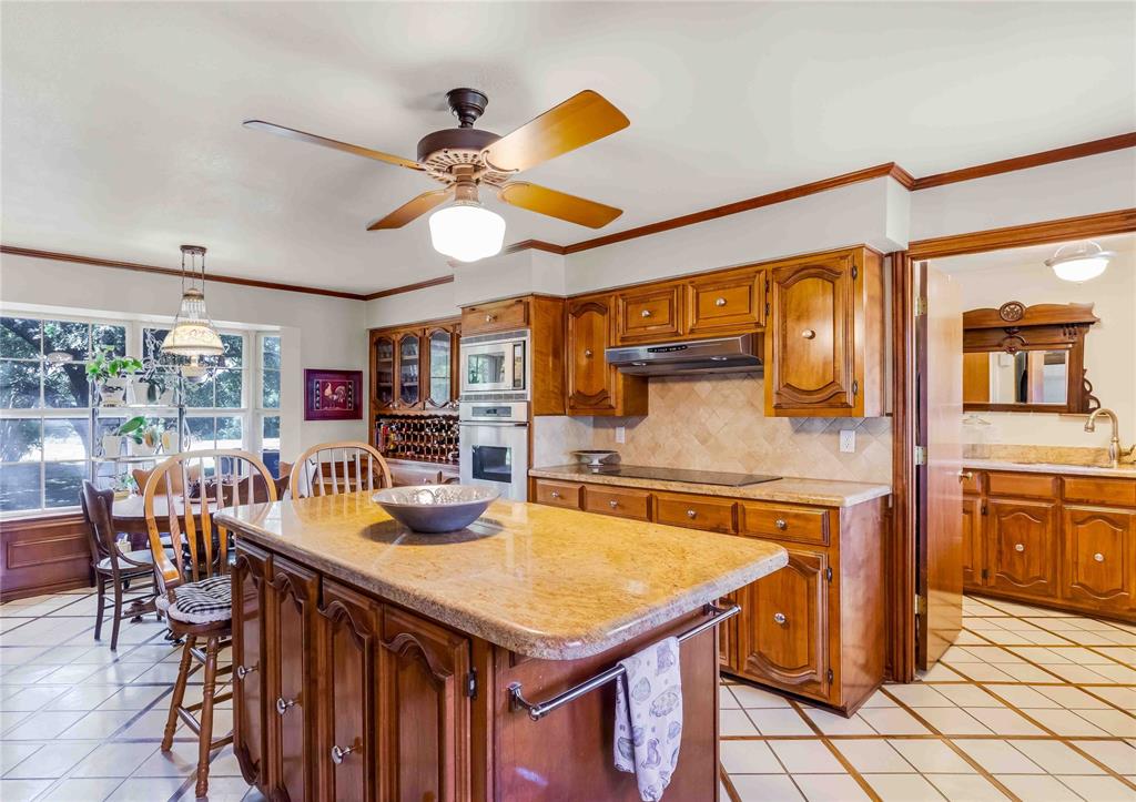 216 McMillen Road Lucas, TX 75002 - Photo 12 of 36 a kitchen with stainless steel appliances granite countertop a table chairs in it and wooden floors
