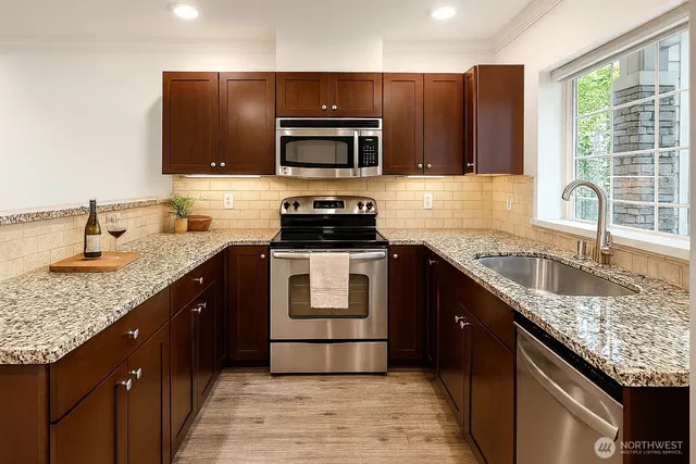 a kitchen with granite countertop a sink and steel appliances