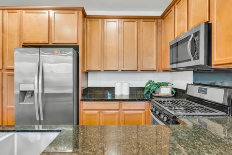 a kitchen with granite countertop a refrigerator and a stove top oven