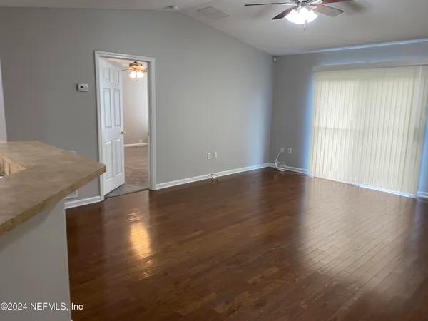 an empty room with wooden floor fan and windows