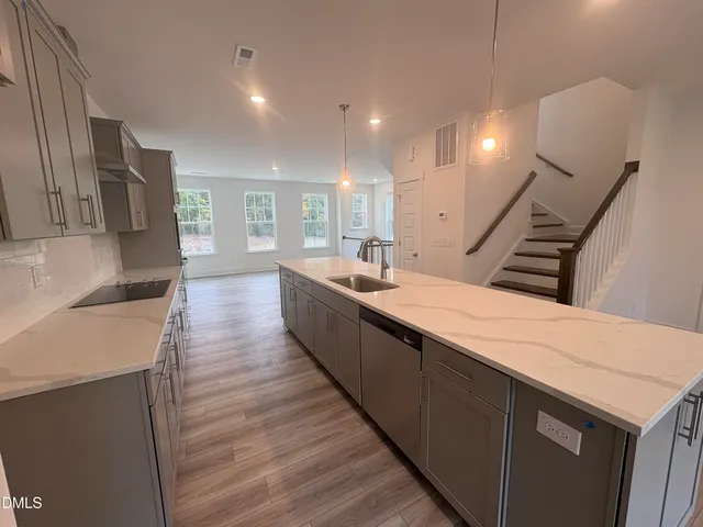 a view of a kitchen with kitchen island a sink wooden floor and black appliances