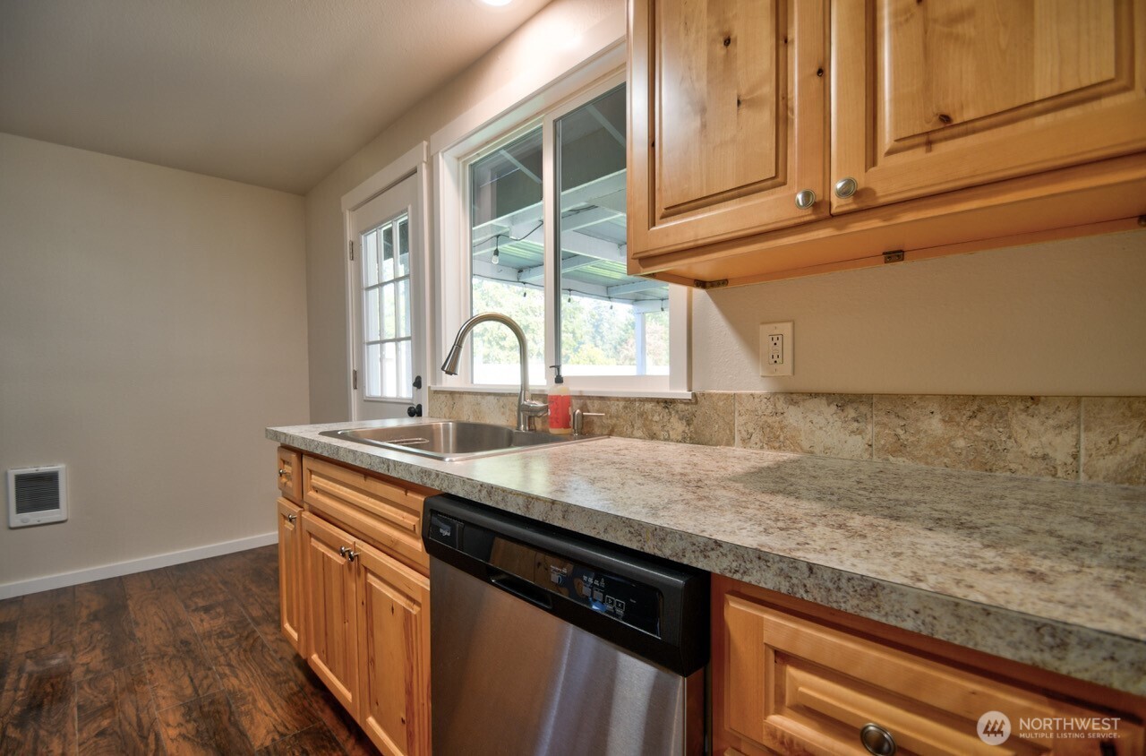 19140 Rosemary Street Southwest Rochester, WA 98579 - Photo 4 of 26 a kitchen with stainless steel appliances granite countertop a sink a stove and a wooden floors