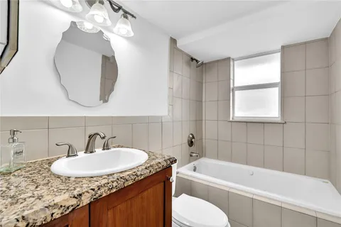 a bathroom with a granite countertop sink mirror toilet and bathtub