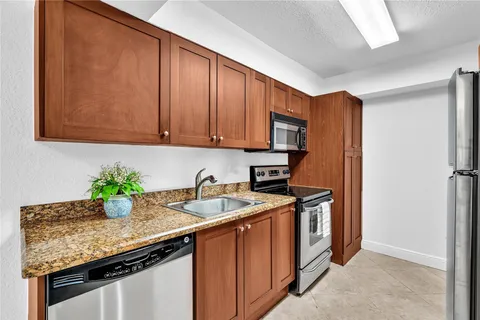 a kitchen with stainless steel appliances granite countertop a sink a stove and a wooden floors