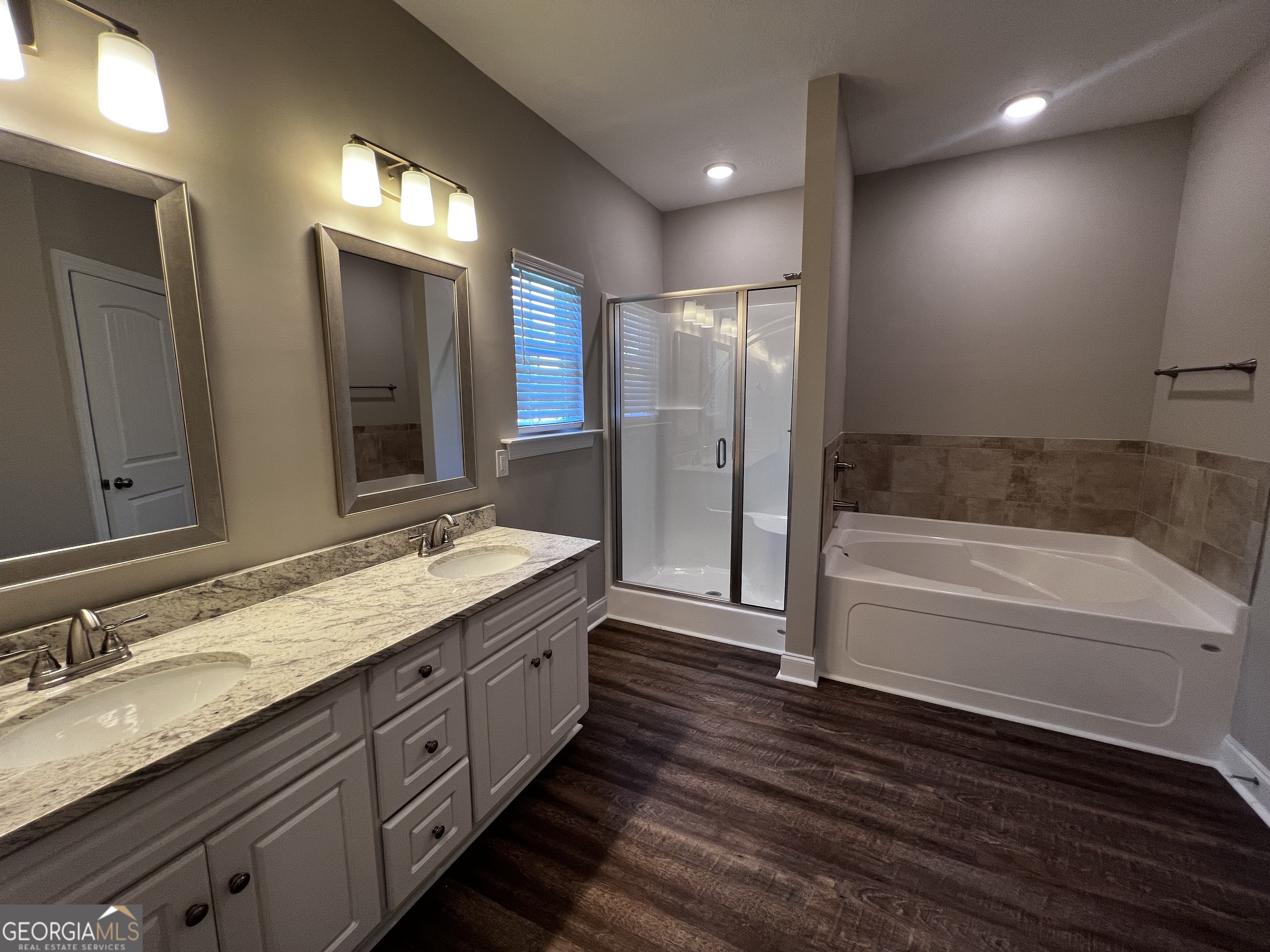 1045 Berkley Court Thomson, GA 30824 - Photo 16 of 32 a bathroom with a granite countertop double vanity sink a mirror and a bathtub